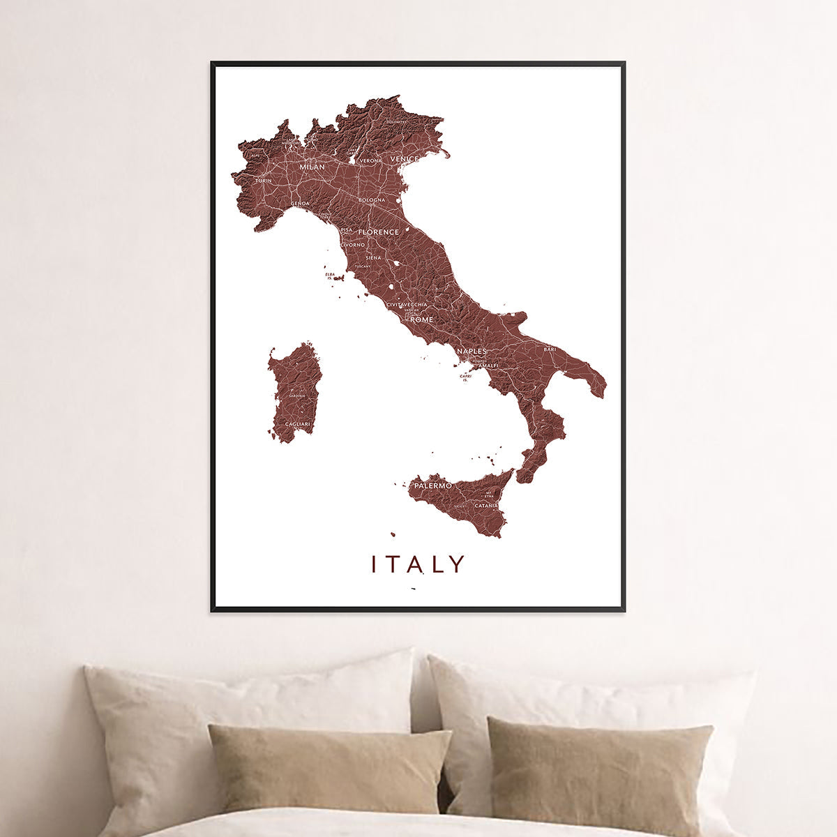 Framed Italy country map print displayed above a bed in a neutral bedroom.