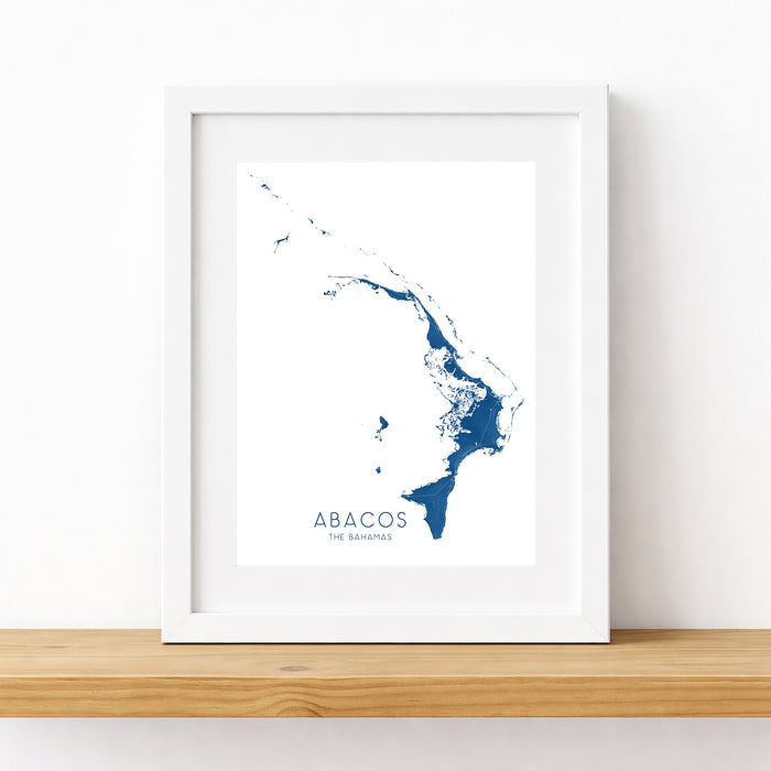 Framed map print of Abacos on a white wall with a wooden shelf.