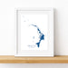 Framed map print of Abacos on a white wall with a wooden shelf.