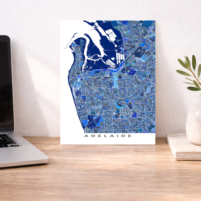 Map of Adelaide on a desk with a laptop and plant