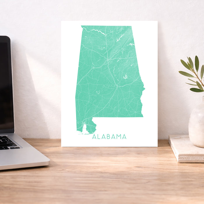 Map of Alabama on a desk with a laptop and plant