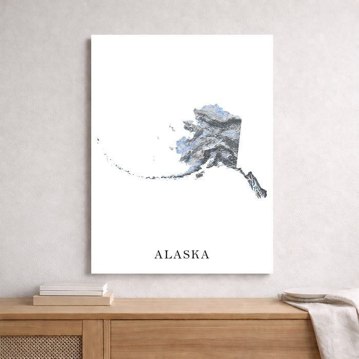 Framed map of Alaska on a wall above a wooden shelf.