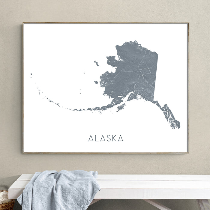 Framed map of Alaska on a wall above a white bench.