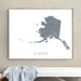 Framed map of Alaska on a wall above a white bench.