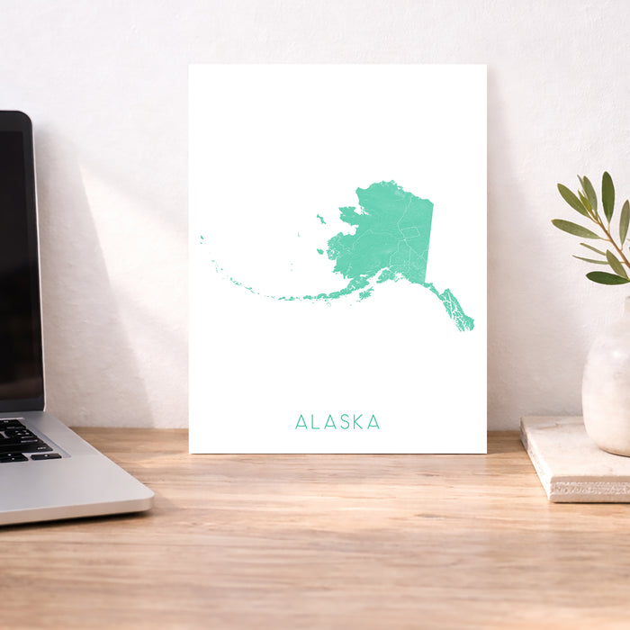 Alaska map print on a desk with a laptop and plant