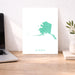 Alaska map print on a desk with a laptop and plant