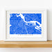 Framed map of Amsterdam on a wooden shelf with a white background