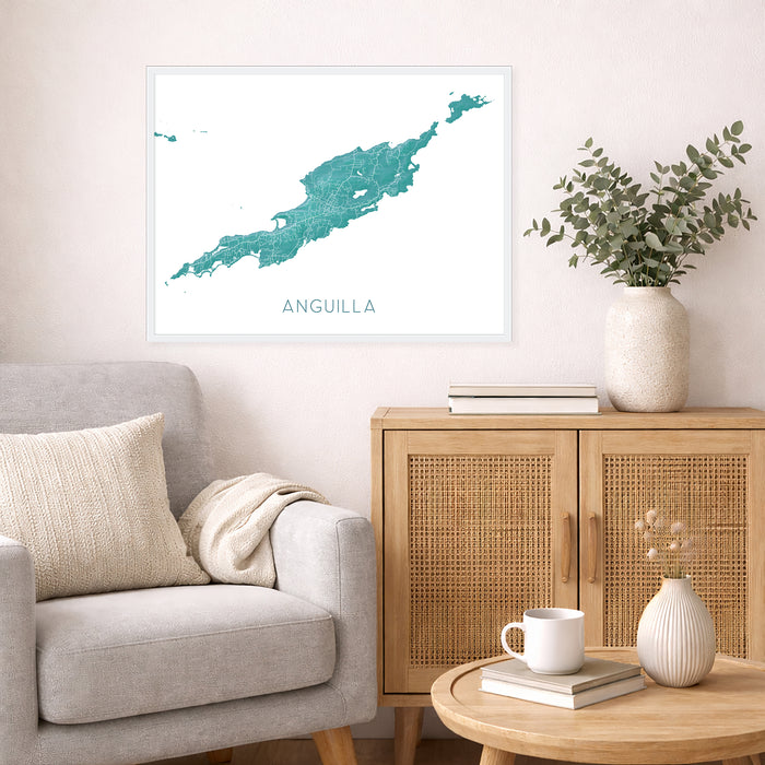 Living room with a map of Anguilla on the wall, a couch, and a side table with a vase and books.