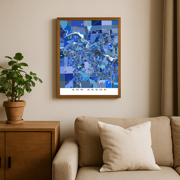 Framed map of Ann Arbor on a wall above a beige sofa with a plant beside it.