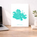 Map of Antigua on a white background displayed on a desk with a laptop and plant.