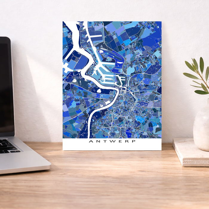 Map of Antwerp on a wall above a desk with a laptop and plant.