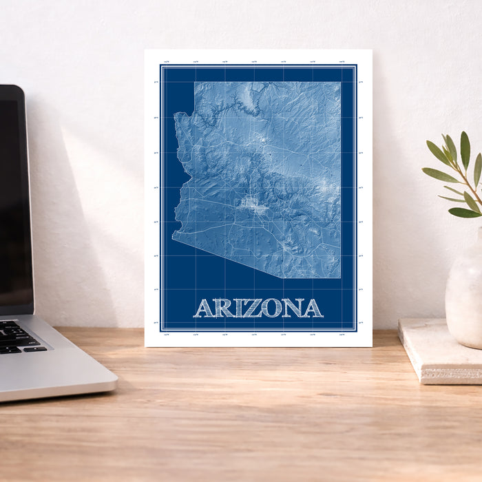 Framed map of Arizona on a desk with a laptop and plant