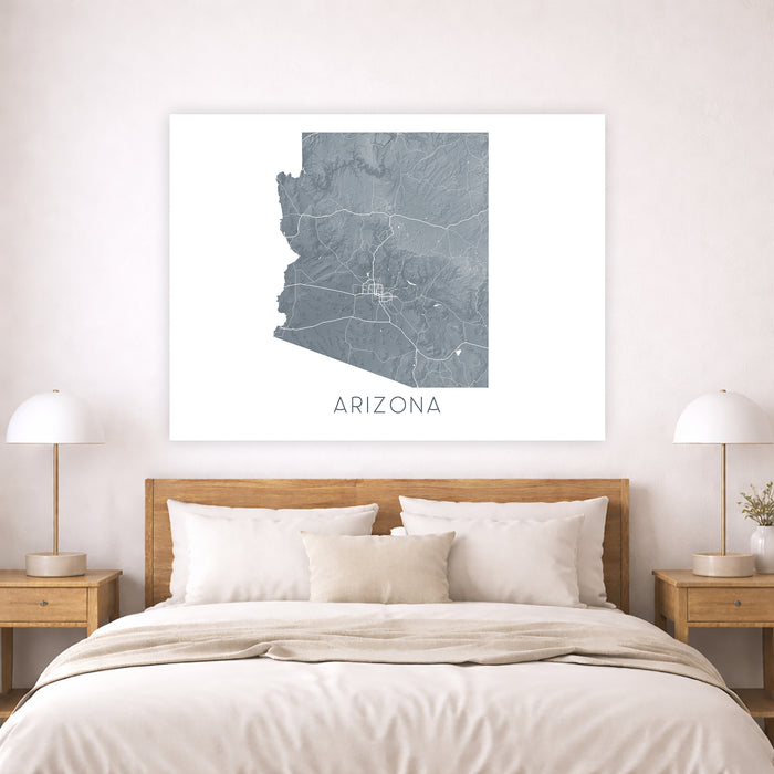 Framed map of Arizona on a wall above a bed in a bedroom.