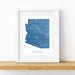 Framed map of Arizona on a wooden shelf with a white background