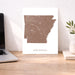 Map of Arkansas on a white background next to a laptop on a wooden desk.