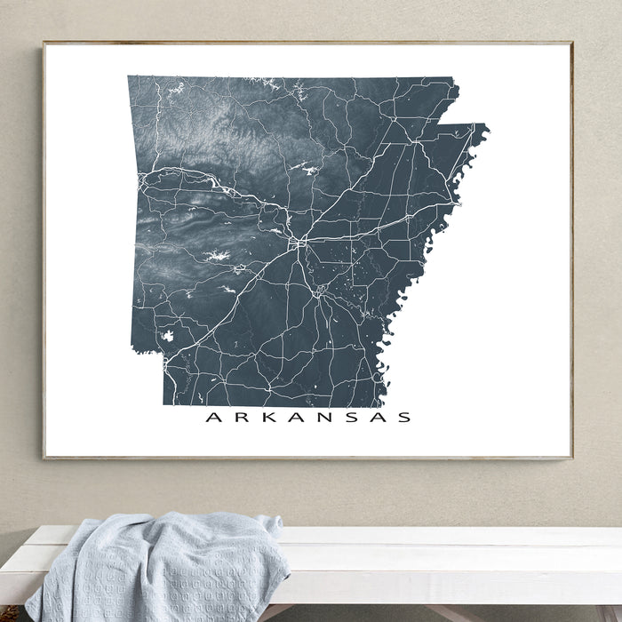Framed map of Arkansas on a wall above a white surface.