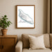 Framed map of Aruba on a wall above a beige sofa with a plant beside it.