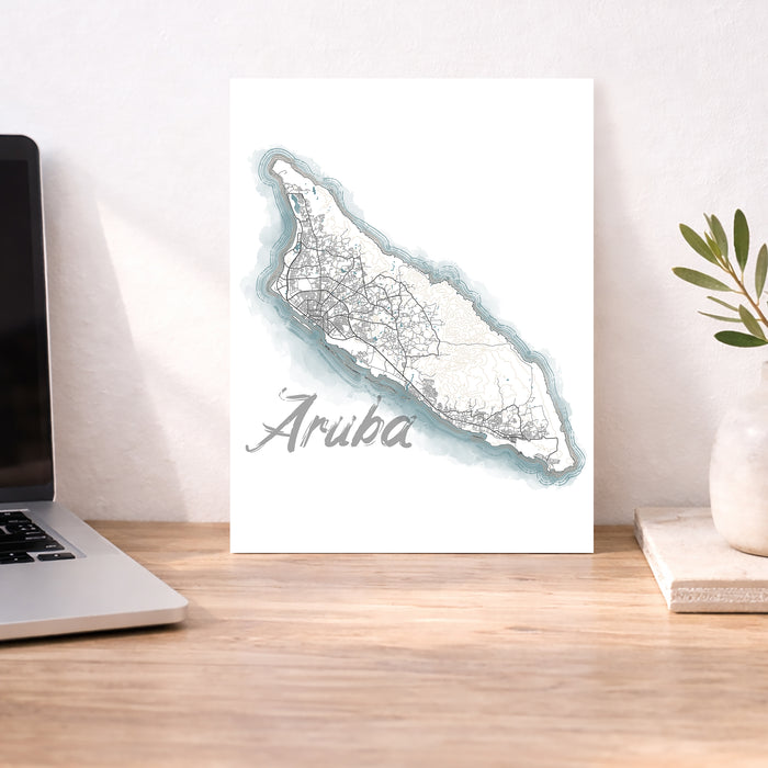 Map of Aruba on a desk with a laptop and plant