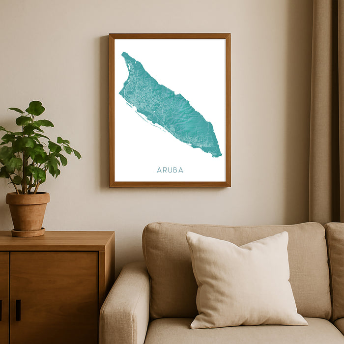 Framed map of Aruba on a wall above a beige sofa with a plant beside it.