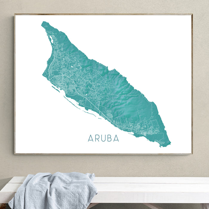 Framed map of Aruba on a wall above a white bench.