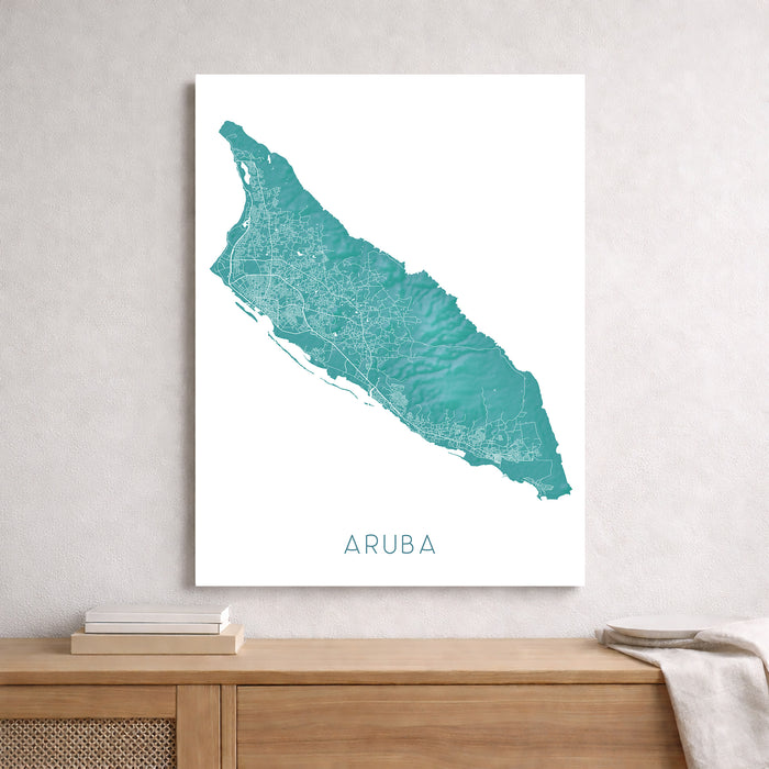 Framed map of Aruba on a wall above a wooden shelf.