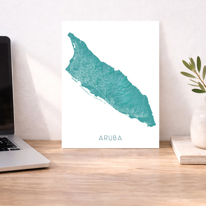 Map of Aruba on a white background next to a laptop on a wooden desk.