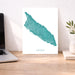 Map of Aruba on a white background next to a laptop on a wooden desk.