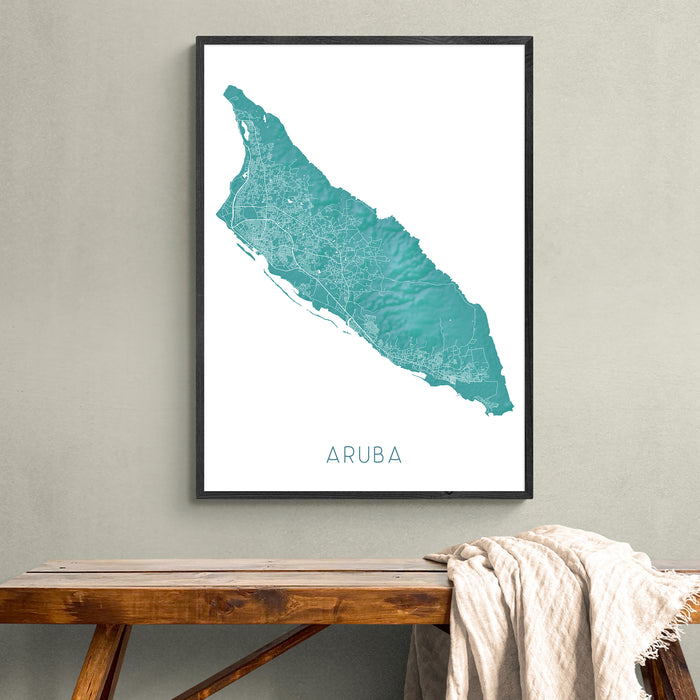 Framed map of Aruba on a wall above a wooden bench.