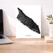 Map of Aruba on a white background next to a laptop on a wooden desk.