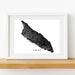 Framed black and white map of Aruba on a wooden shelf.
