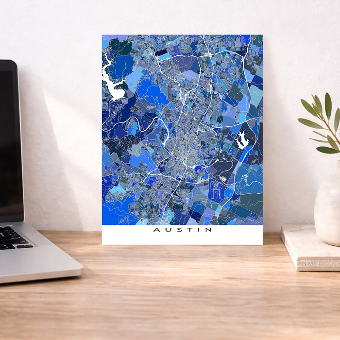 Map of Austin on a wall above a desk with a laptop and plant.