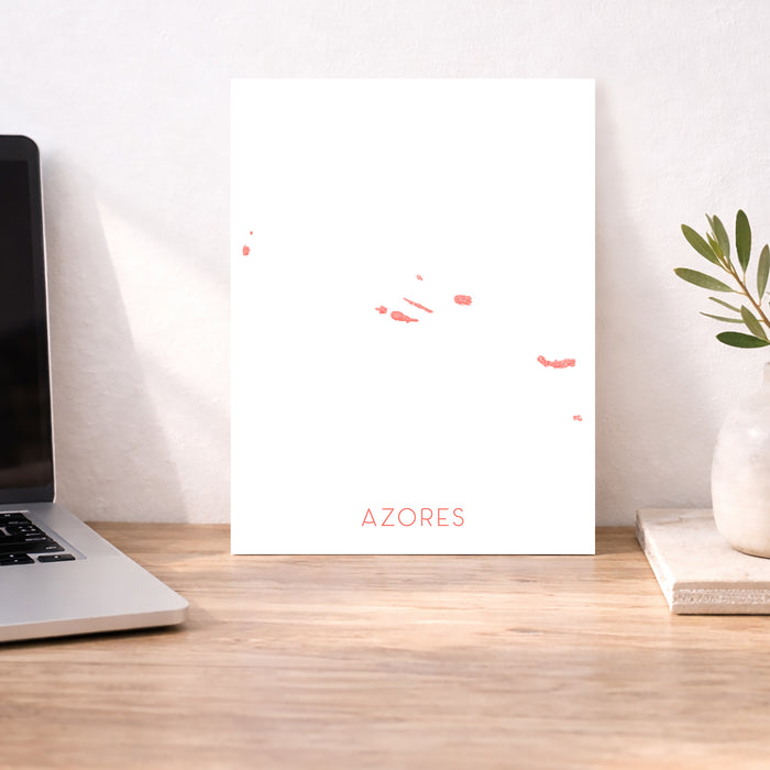 Laptop on a desk with a decorative paper featuring 'Azores' text and a plant in the background.