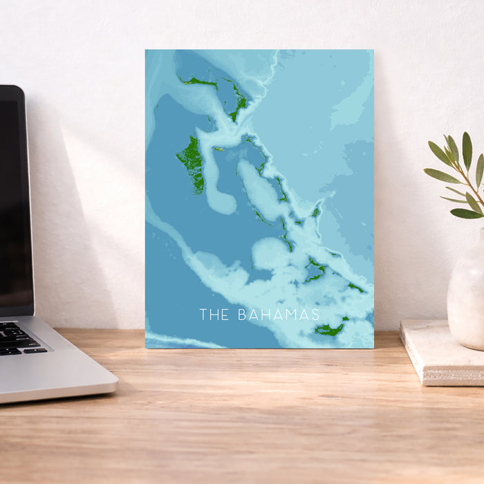 Map of The Bahamas on a desk with a laptop and plant