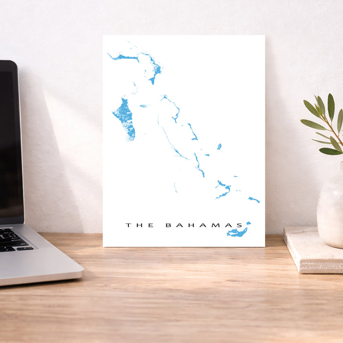 Map of The Bahamas on a white background next to a laptop on a wooden desk.
