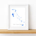 Framed map of The Bahamas on a white wall with a wooden shelf.