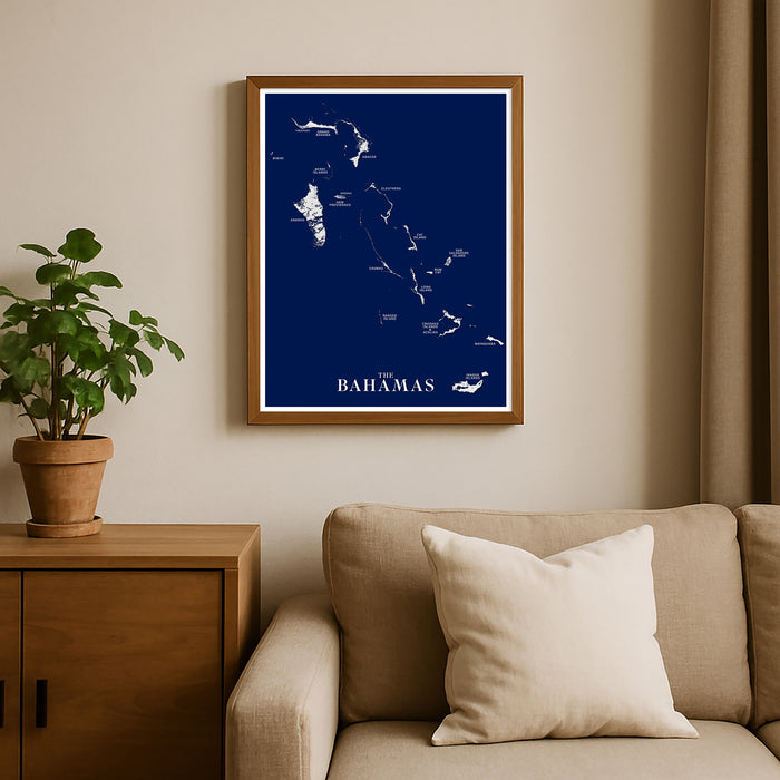 Framed map of the Bahamas on a wall above a beige sofa with a plant beside it.