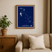 Framed map of the Bahamas on a wall above a beige sofa with a plant beside it.