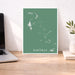Map of The Bahamas on a green background in a white frame on a desk.