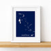 Framed map of The Bahamas on a white wall with a wooden shelf.