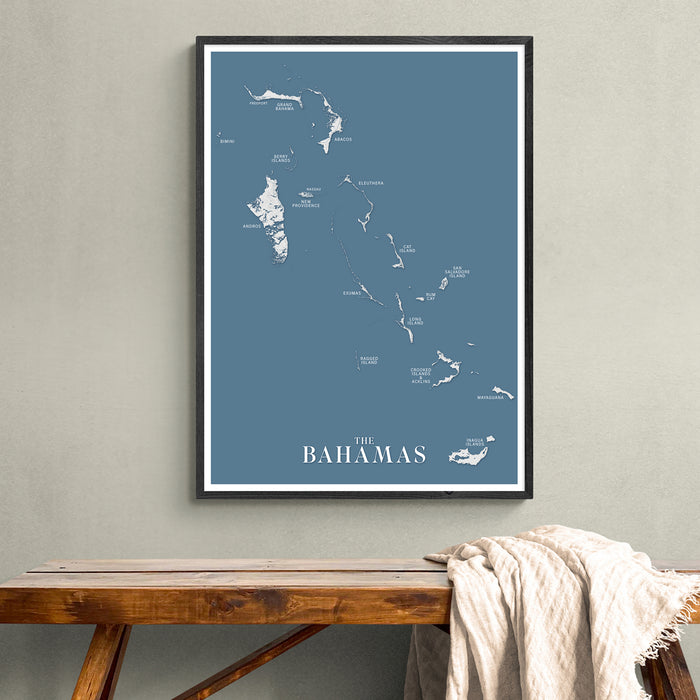 Framed map of The Bahamas on a wall above a wooden bench.