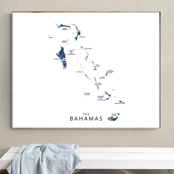 Framed map of The Bahamas on a wall above a white bench.