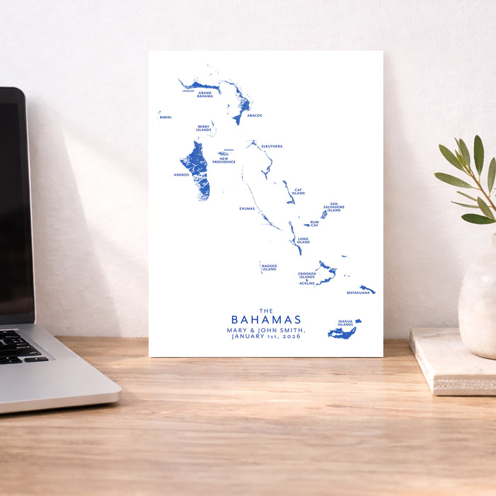 Map of The Bahamas on a white background next to a laptop on a wooden desk.