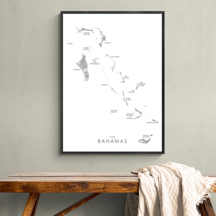 Framed map of The Bahamas on a wall above a wooden bench.