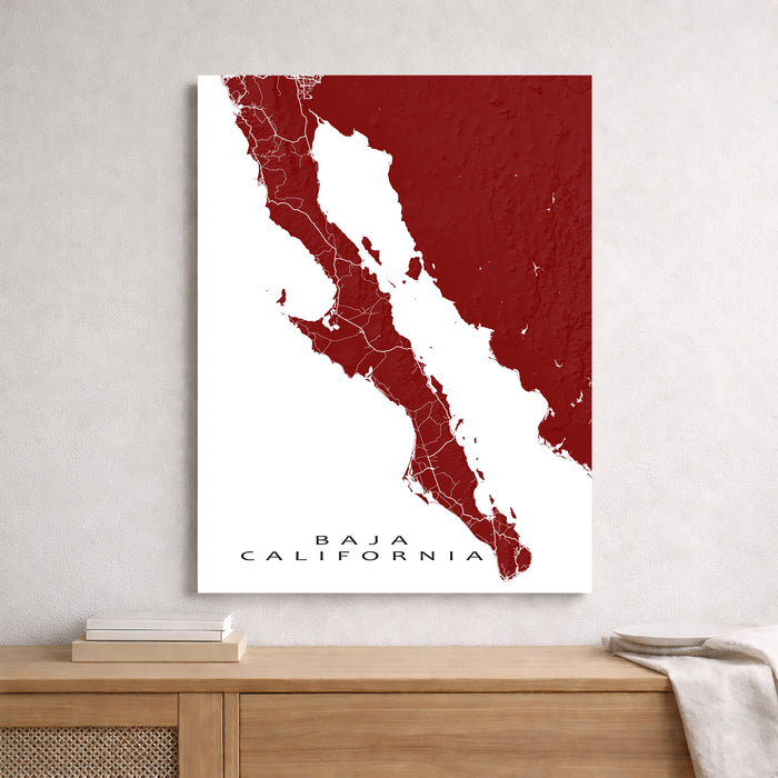 Map of Baja California in red and white on a wall above a wooden shelf.
