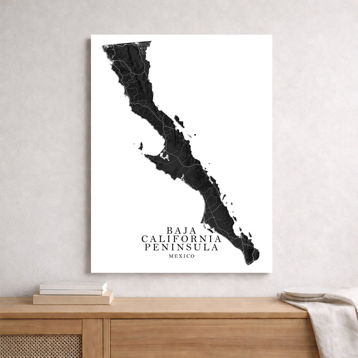 Map of Baja California Peninsula framed on a wall above a wooden shelf.
