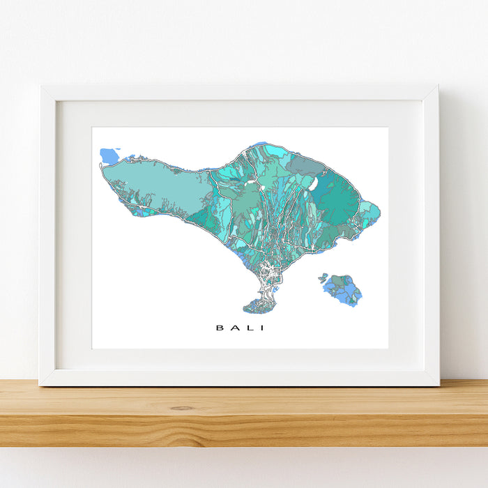 Framed map of Bali with a white border on a wooden surface.