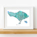 Framed map of Bali with a white border on a wooden surface.