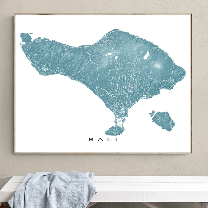 Framed map of Bali on a wall above a white bench.