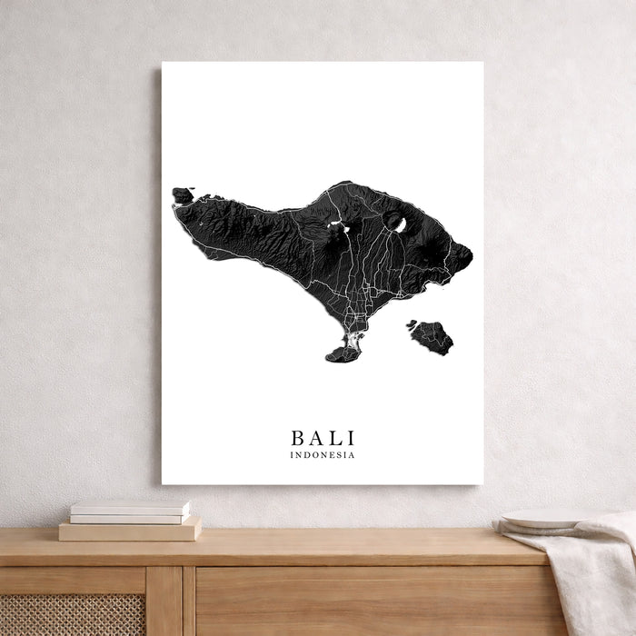 Map of Bali, Indonesia on a white background in a frame on a wooden surface.