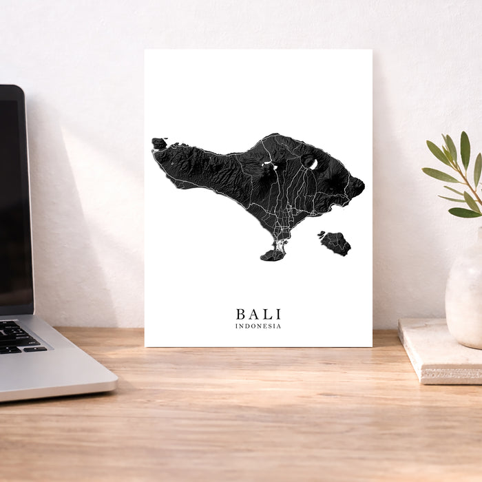 Map of Bali on a desk with a laptop and plant